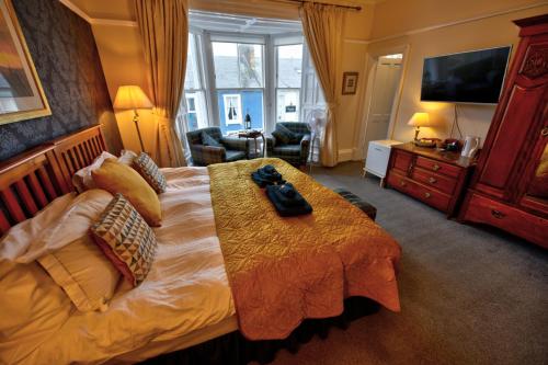 um quarto com uma cama grande e uma televisão em Burnside Guest House em Ayr