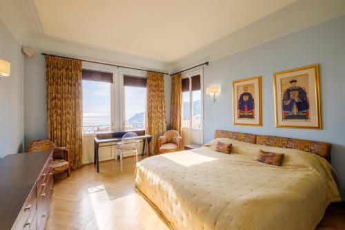 a bedroom with a large bed and a desk and window at Villa Sorrentina in Villefranche-sur-Mer