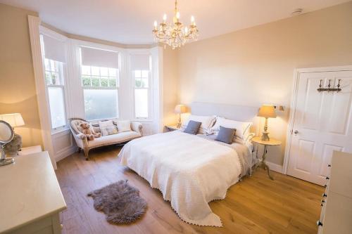 Un dormitorio con una gran cama blanca y una lámpara de araña. en Swanky London pad in Putney en Londres
