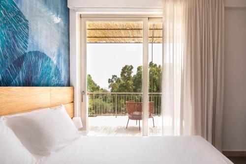 a bedroom with a bed and a balcony with a window at Luna Minoica Suites and Apartments in Montallegro