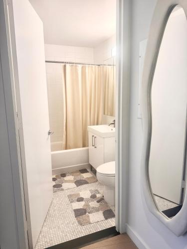 a bathroom with a white toilet and a mirror at Exquisite Urban Oasis: Luxury 1 Bedroom Retreat in Downtown Manhattan in New York