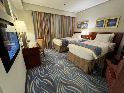 a hotel room with two beds and a flat screen tv at Al Safwah Hotel Third Tower in Makkah