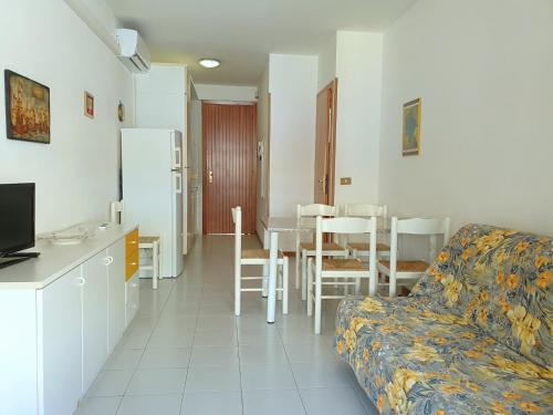 ein Wohnzimmer mit einem Sofa, einer Küche und einem Tisch in der Unterkunft Lovely flat in Bibione Pineda 100m from the beach in Bibione