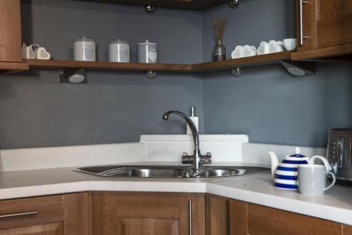 a kitchen with a stainless steel sink and wooden cabinets at Bathsheba, Ocean 1 in Newquay