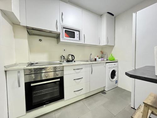 uma cozinha com armários brancos e uma máquina de lavar e secar roupa em Ile Aina Exterior Nuevo Peña em Madri