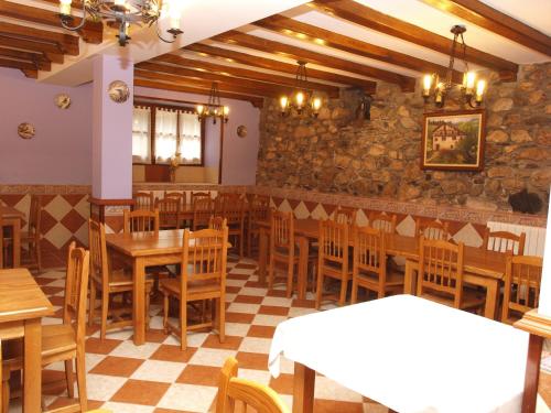 a restaurant with wooden tables and chairs and a stone wall at Hostal Rural Onbordi in Lesaka