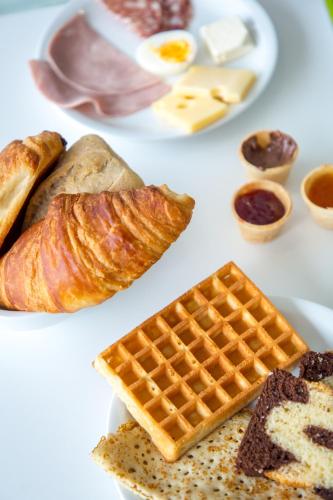 a table with a plate of bread and waffles and eggs at Ibis Budget Fréjus St Raphaël centre in Fréjus