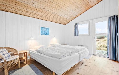 a bedroom with a bed and a chair and a window at Pallas in Fanø
