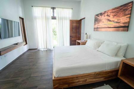 ein Schlafzimmer mit einem großen weißen Bett in einem Zimmer in der Unterkunft Cheerful 2 bedroom Villa with Pool in Benque Viejo del Carmen