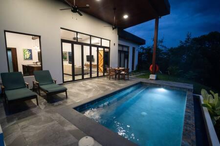 a swimming pool with two chairs and a house at Modern Villa Overlooking Macal River Valley in Benque Viejo del Carmen