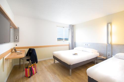 a hotel room with two beds and a desk at Ibis Budget Fréjus St Raphaël centre in Fréjus