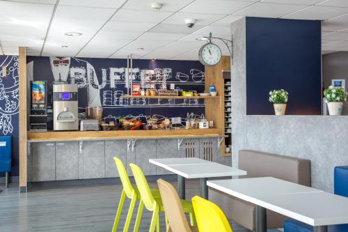 a restaurant with white tables and yellow chairs at Ibis Budget Fréjus St Raphaël centre in Fréjus