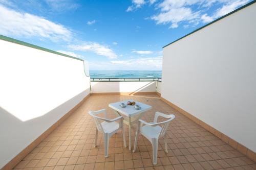 uma varanda com uma mesa e 2 cadeiras em Hotel Roma Sul Mare em Roseto degli Abruzzi