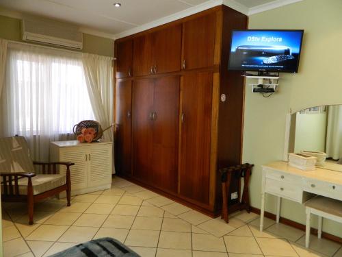 a living room with a tv on a wall at Birdcage B&B in Amanzimtoti