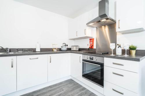 a white kitchen with white cabinets and a stove at Luxury Selly Oak Apartment near QE & Uni - Secure Parking - 20CC in Birmingham