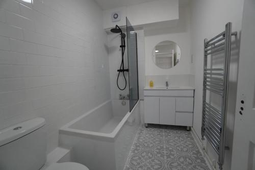 Baño blanco con bañera y lavamanos en Seafront Medina, en Brighton & Hove