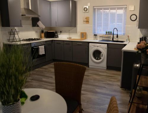 a kitchen with a sink and a washing machine at Cosy Modern Flat (NEC/BHX Stays) in Marston Green