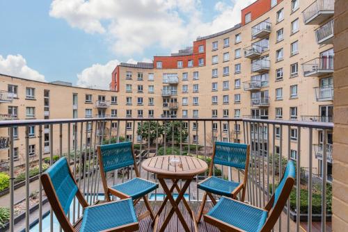 a patio with chairs and a table on a balcony with buildings at 5-Star Kings Cross Home with Gym - Central London in London