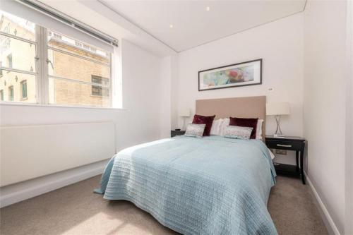 a white bedroom with a bed and a window at Newly Furnished Penthouse Mayfair in London