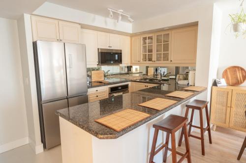 a kitchen with a refrigerator and a counter with stools at Boutique Suite in Downtown Toronto, Free Parking! in Toronto