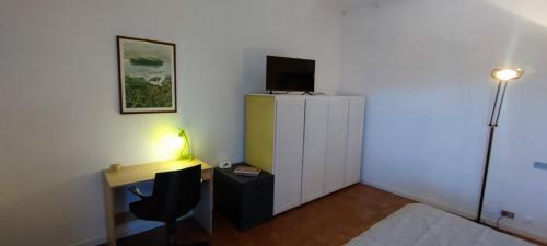 ein Schlafzimmer mit einem Schreibtisch und einem TV auf einem Schrank in der Unterkunft Casa Robert in Alessandria