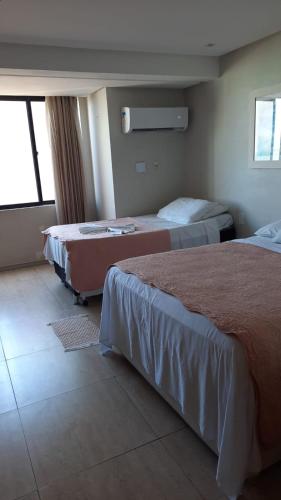 a hotel room with two beds and a window at Atlântico Flat in Natal