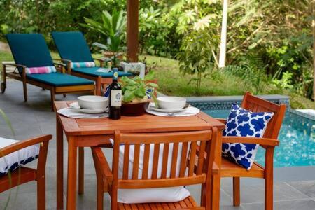 una mesa de madera con sillas y una botella de vino en Private Modern Villa Near Resort District en Benque Viejo del Carmen