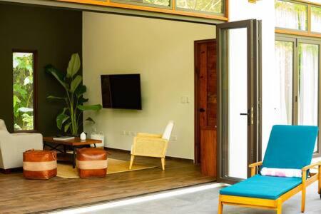 Private Modern Villa Near Resort District في Benque Viejo del Carmen: غرفة معيشة مع كرسيين وتلفزيون