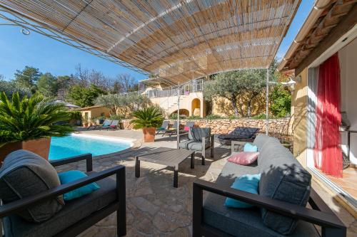 une terrasse avec un canapé et des chaises ainsi qu'une piscine dans l'établissement Le Chemin de la Grave - Maison avec piscine, à Aups