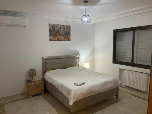a white bedroom with a bed and a window at Appartement jardin de Carthage tunisia in Tunis