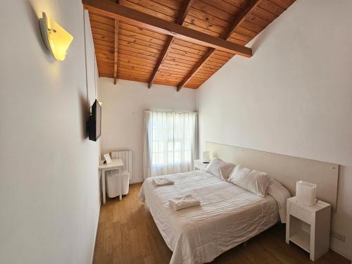 - une chambre avec un lit blanc et un plafond en bois dans l'établissement SH Hotel & Spa de Mar Samay Huasi, à Puerto Madryn