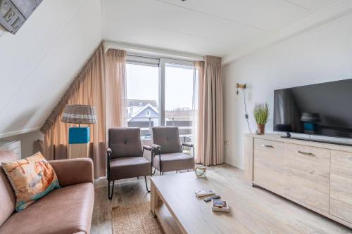 a living room with a couch and a tv at Anna 222 in De Koog