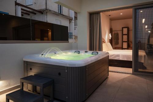 Baño con bañera y dormitorio en el fondo en Cove Luxury Suites, en Agia Galini
