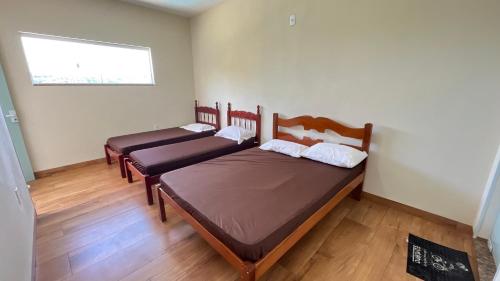 two beds in a room with a window at Chácara do André. in Serra Negra