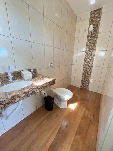 a bathroom with a toilet and a sink at Chácara do André. in Serra Negra
