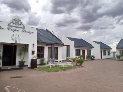 a row of white buildings with chairs in a courtyard at The Cape Lodge in Upington