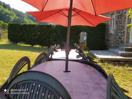 a table with a red umbrella on top of it at Gite au sein du Parc des Volcans d'Auvergne, tous commerces à pied in Neussargues-Moissac