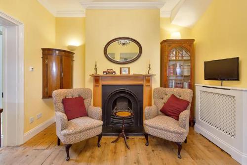 a living room with two chairs and a fireplace at Windsor/Legoland/Ascot charming 3BR home in centre in Windsor