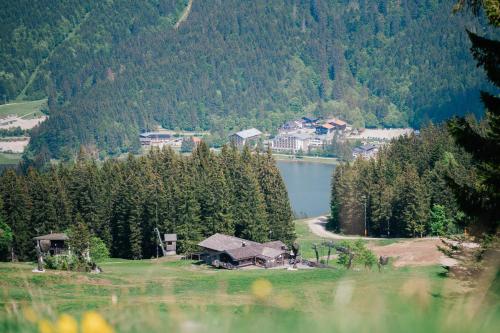 a house on a hill next to a lake at Arabella Alpenhotel am Spitzingsee, a Tribute Portfolio Hotel in Spitzingsee