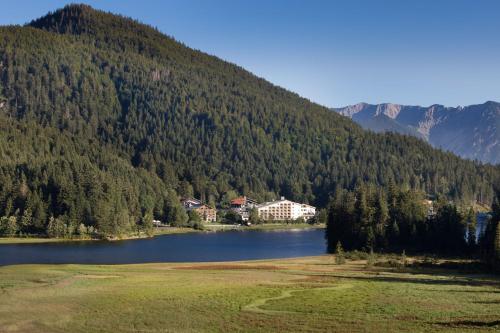 a lake in front of a mountain with a house at Arabella Alpenhotel am Spitzingsee, a Tribute Portfolio Hotel in Spitzingsee
