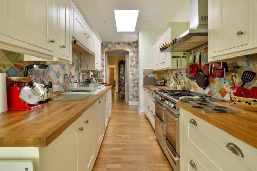 a large kitchen with white cabinets and wooden floors at Windsor/Legoland/Ascot charming 3BR home in centre in Windsor