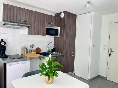 une cuisine avec des placards en bois et une table blanche avec une plante dans l'établissement Le Cocoon Quatre Pavillons Lormont, à Lormont