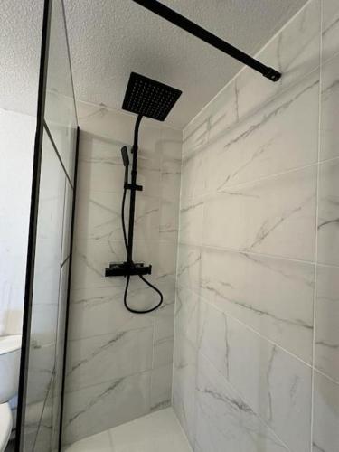 La salle de bains est pourvue d'une douche et de murs en marbre blanc. dans l'établissement Le Cocoon Quatre Pavillons Lormont, à Lormont