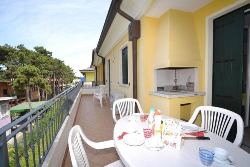 uma mesa branca e cadeiras numa varanda com uma cozinha em Coastal escape modern flat with Wi-Fi em Bibione