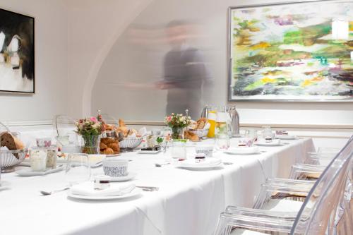 a row of tables with white plates and flowers at Schlossberghotel in Graz