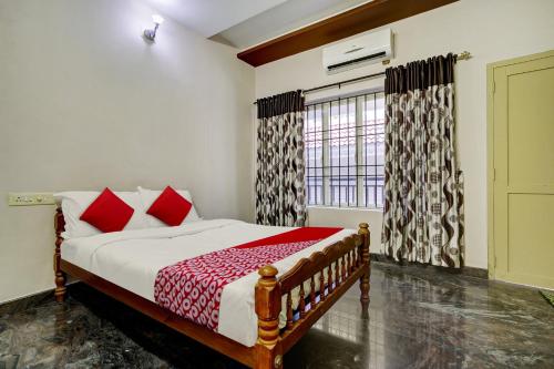 a bedroom with a bed with red pillows and a window at OYO Hi 5 Apartments in Cochin