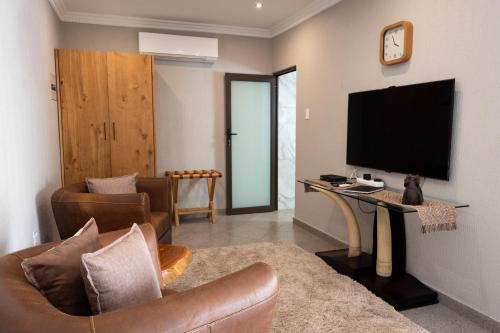 a living room with a couch and a television on a wall at Modjadji Estate Lodge & Spa in Grietjie Nature Reserve