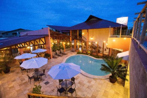 um hotel com piscina, mesas e guarda-sóis em Vivá Barra Hotel Pousada na Barra de São Miguel