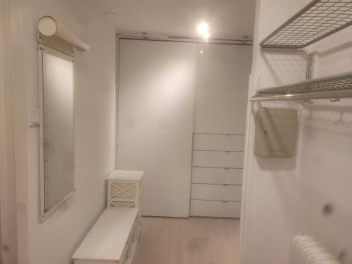 um armário branco com um banco e um espelho em Garsoniera em Malmo