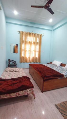 a bedroom with two beds and a ceiling fan at ARJUN PAYING GUEST HOUSE in Ayodhya